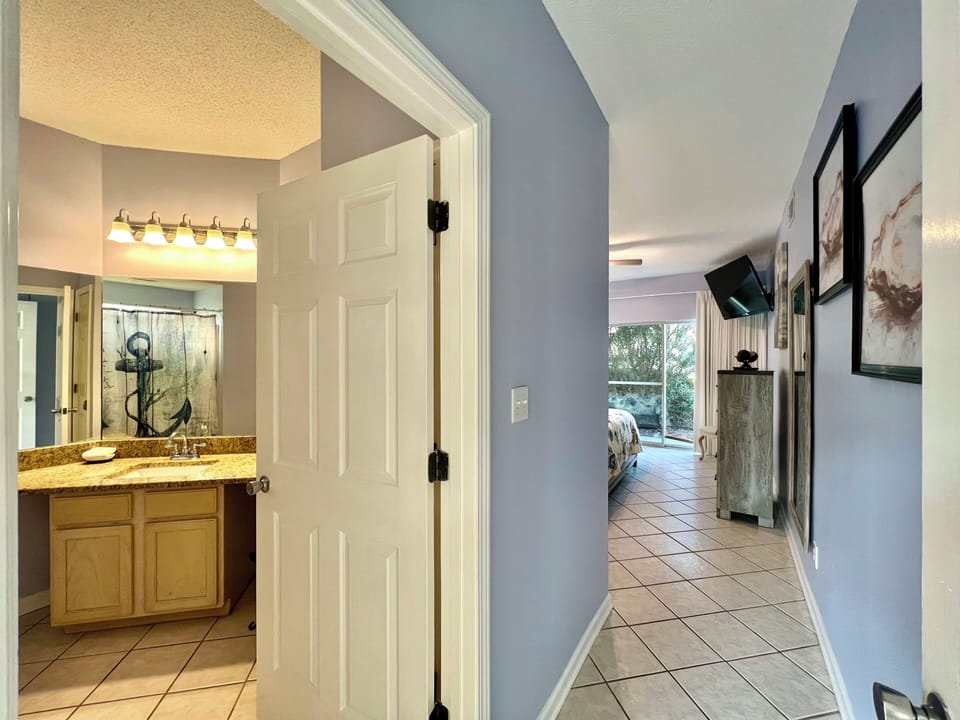 Your private bathroom features granite counters and nautical charm, while the hallway leads to your peaceful bedroom retreat.