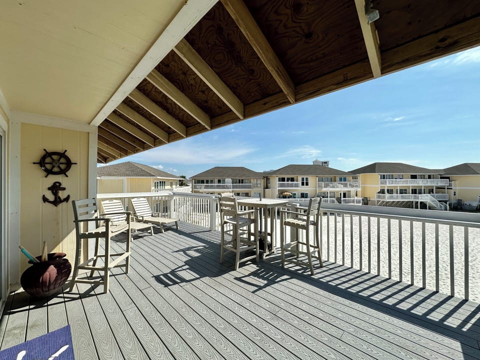 Your spacious deck offers shaded seating with nautical touches, perfect for morning coffee or evening drinks while overlooking the sandy beach setting.
