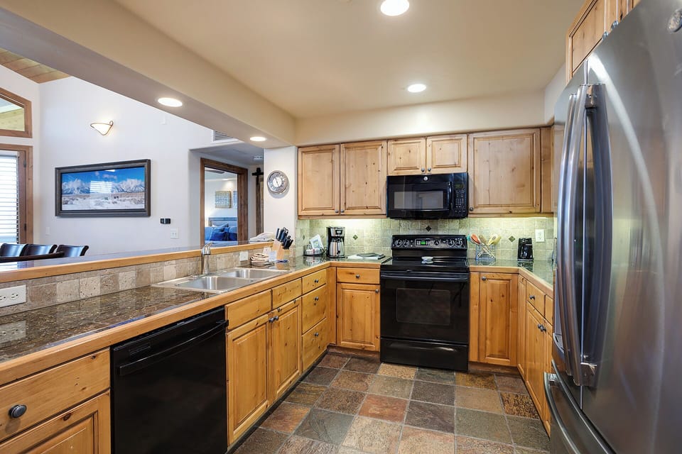 Your spacious kitchen features warm wood cabinets, granite countertops, and modern appliances for creating memorable meals together.