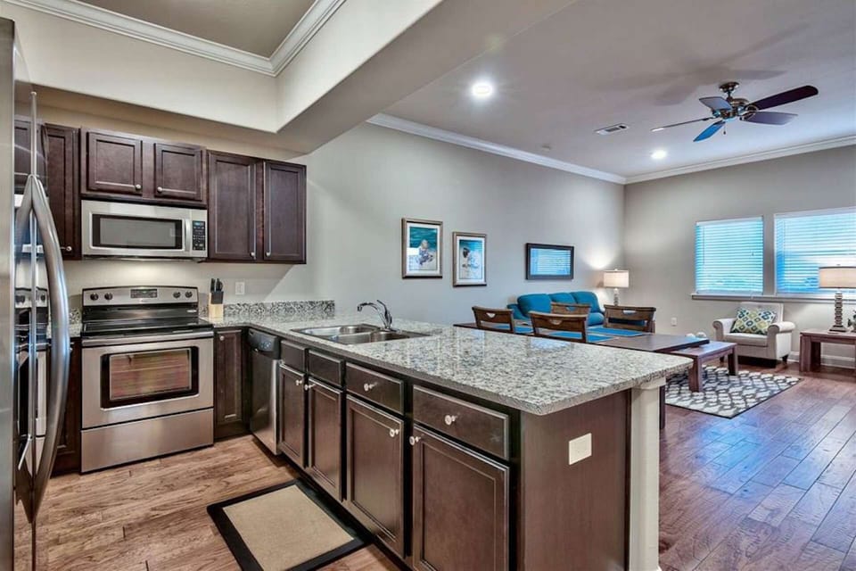 Fully equipped kitchen with stainless steel appliances, granite counter, dark wood cabinetry