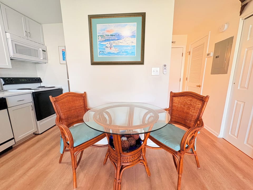 Gather around your charming glass-top dining table with wicker chairs, perfectly positioned between your fully equipped kitchen and cozy living space.