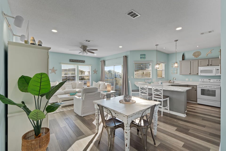 Your open-concept retreat features coastal-themed living with soft turquoise walls, modern kitchen, and comfortable seating perfect for relaxation.