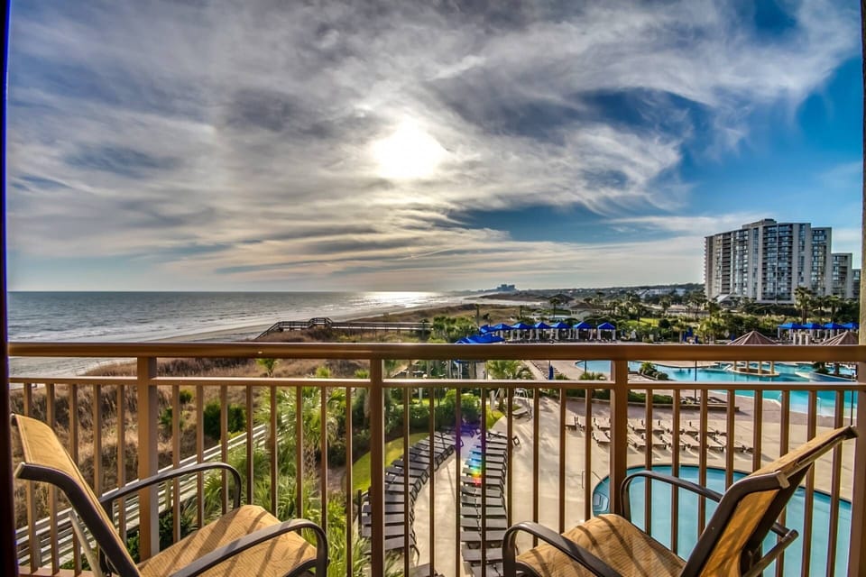 "Private side balcony with panoramic coastline views overlooking North Beach Resort's award-winning pool complex.