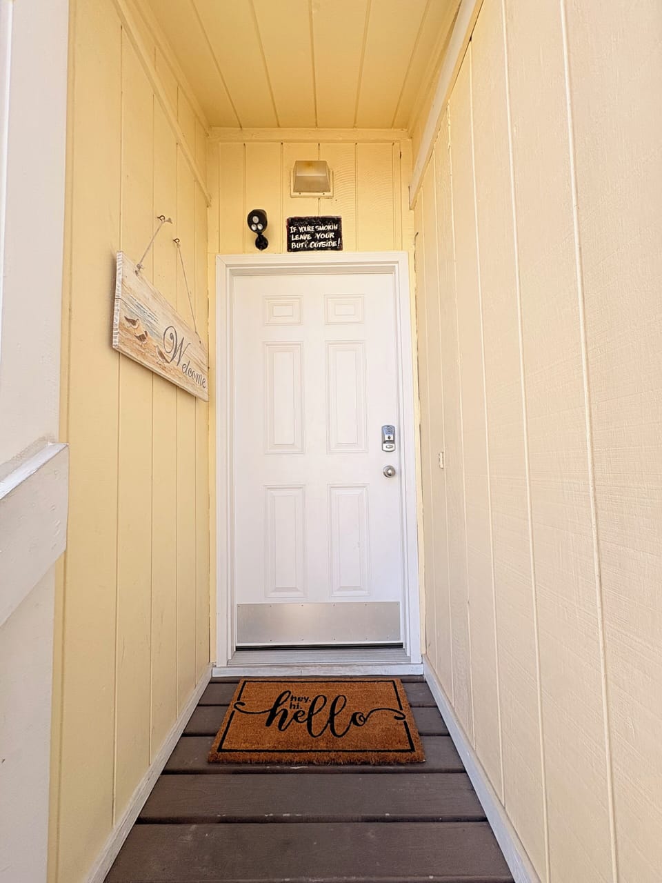 Step through your private entrance into a welcoming covered porch area, where thoughtful details like the cheerful doormat set the tone for your stay.