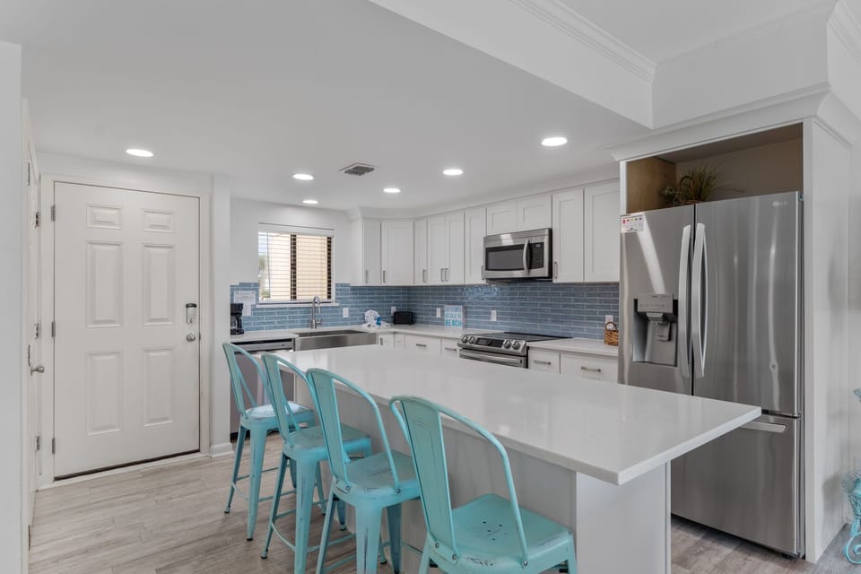 Cook together in this bright, fully-equipped kitchen with modern appliances and cheerful turquoise seating at the spacious island.