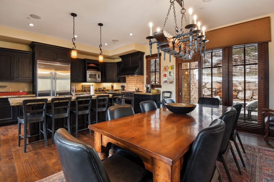 Gather around this stunning wooden dining table where memorable meals and conversations unfold beneath elegant chandelier lighting.