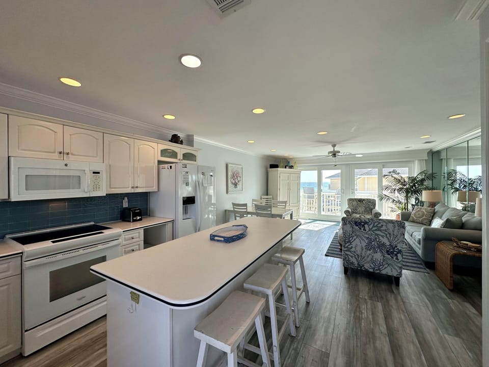 Your bright, open-plan living space seamlessly blends kitchen and lounge with stunning ocean views through expansive windows.