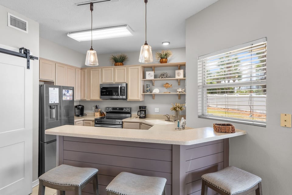 Whip up your favorite meals in this bright, fully-equipped kitchen. Pendant lighting and breakfast bar seating make cooking and dining a breeze. Natural light flows through the windows, creating a warm, welcoming space.
