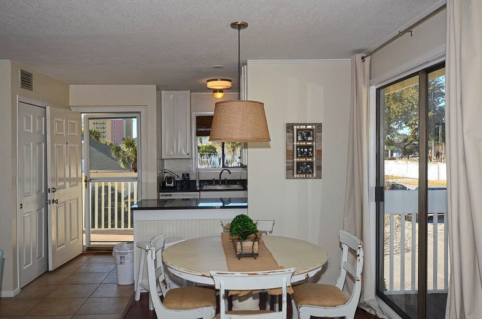 Your coastal dining space beckons with a charming round table and modern kitchen, perfect for morning coffee or evening meals together.