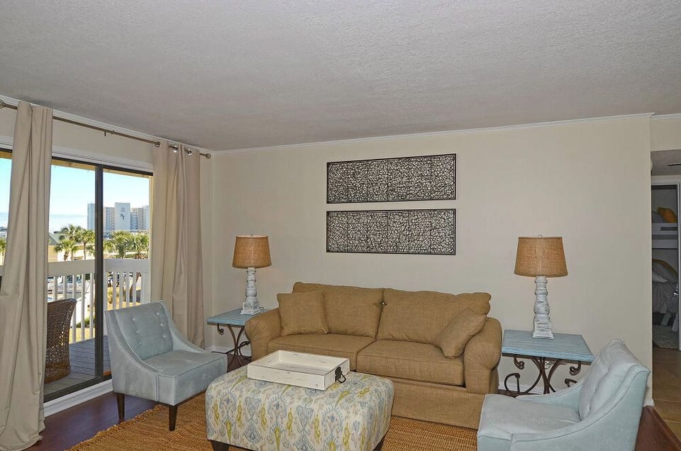 Unwind in your elegantly appointed living room with soft coastal hues, plush seating, and sweeping city views from your private balcony.