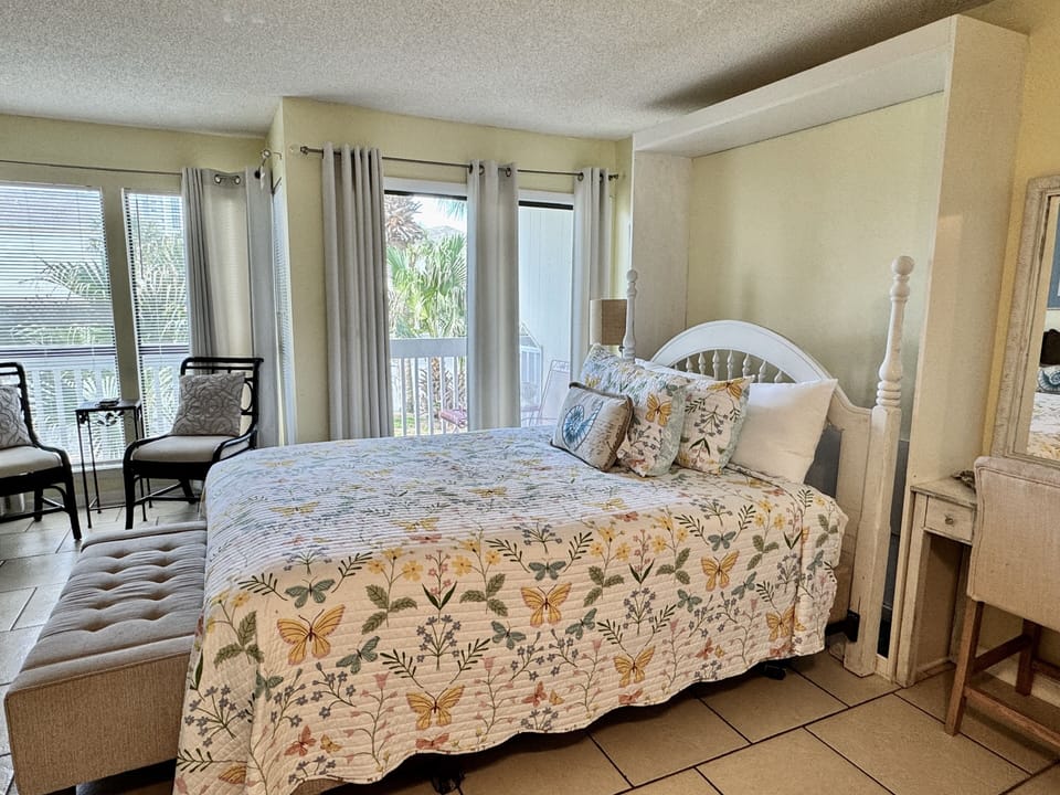 Sink into your cozy four-poster bed adorned with charming floral linens. Natural light streams through your private balcony doors as you unwind.