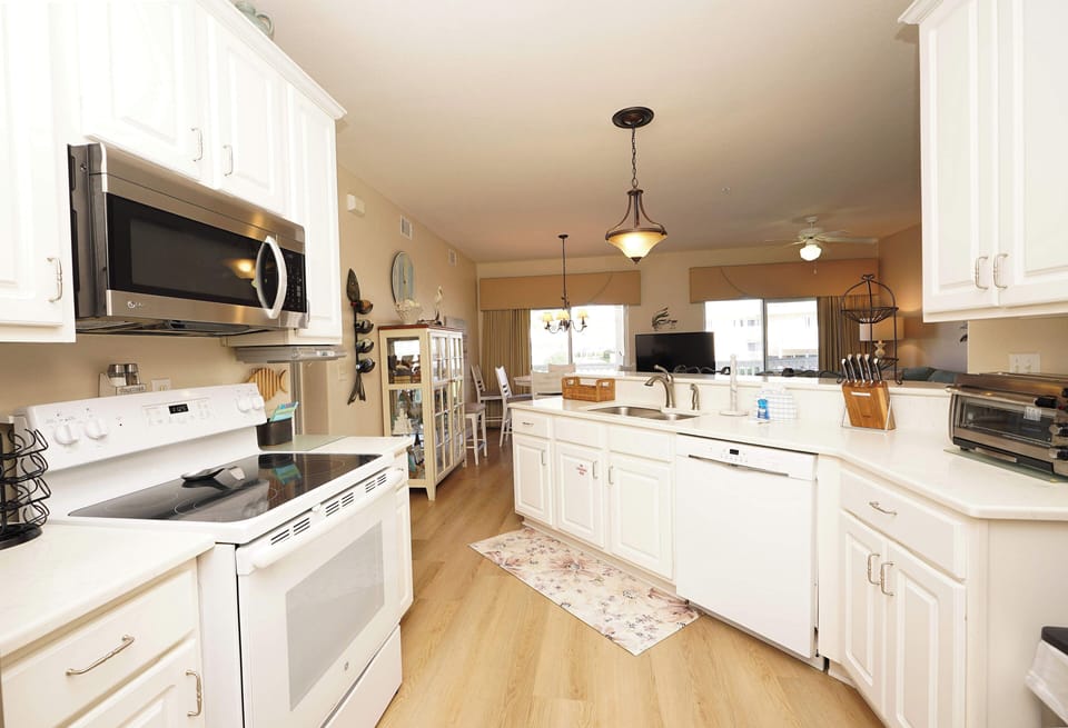 Your spacious kitchen awaits with gleaming white cabinets, modern appliances, and plenty of counter space for preparing meals together.