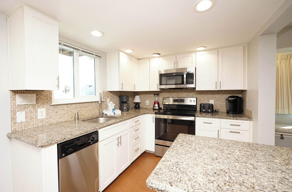 Your fully equipped kitchen sparkles with granite counters, stainless appliances, and bright natural light—perfect for creating memorable vacation meals.