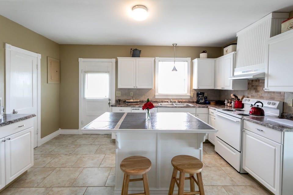 Spacious fully-equipped kitchen featuring a stove/oven, dishwasher, large refrigerator, coffeemaker, and ample prep space