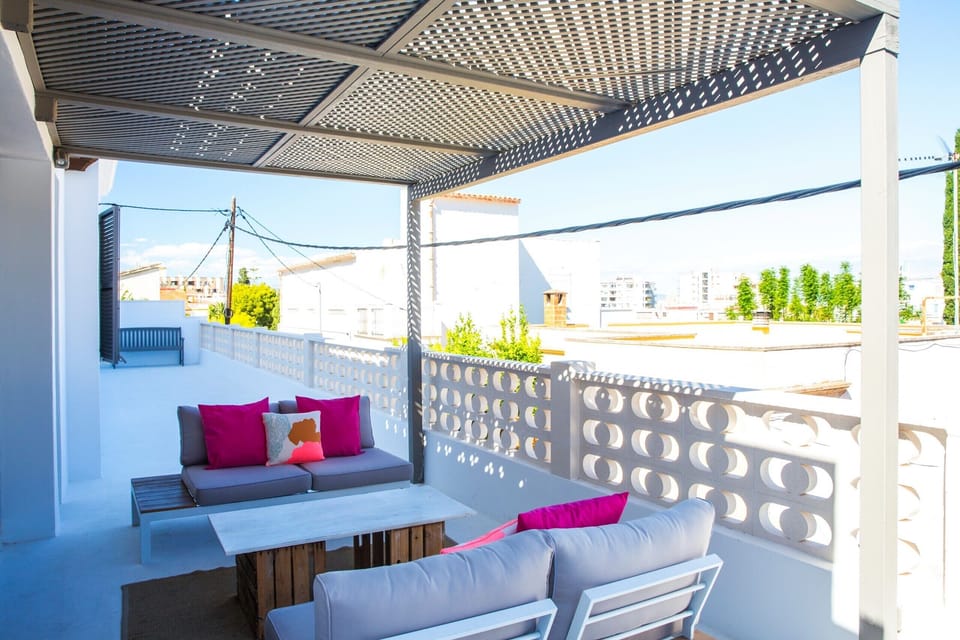 The holiday villa Terra Blanca in Palma de Mallorca has several terraces and a swimming pool. The terrace seen in this photo is located on the street side, next to the living room, and is covered with a pergola.