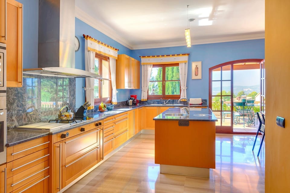 Large kitchen with an island-breakfast bar, well-lit with views of the island's mountain range.