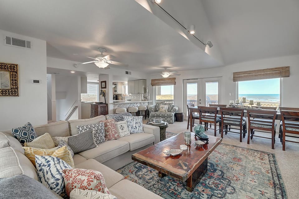 Relax in your stunning oceanfront living room, where coastal views stretch endlessly beyond floor-to-ceiling windows and comfortable seating invites peaceful moments.