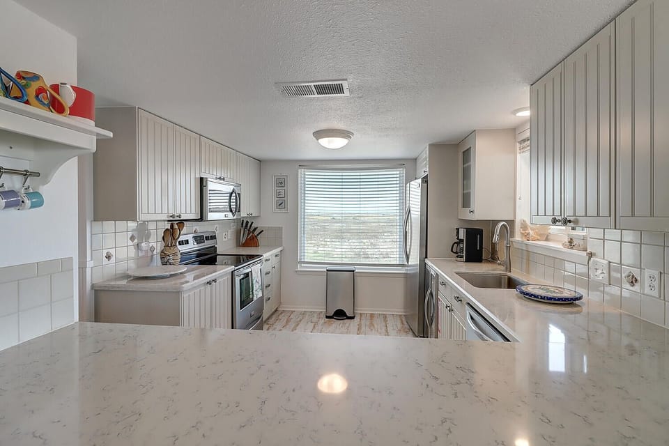 Cook your favorite meals in this bright, fully-equipped kitchen featuring quartz countertops and modern appliances.