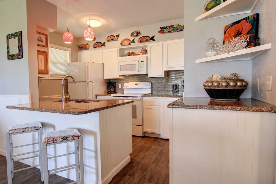 Your fully equipped kitchen features granite countertops, stainless appliances, and charming coastal décor perfect for preparing meals during your stay.