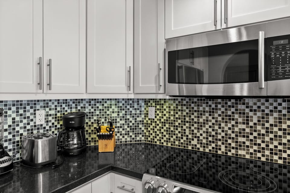 Your modern kitchen awaits with sleek granite counters, stainless appliances, and mosaic backsplash—perfect for preparing morning coffee or home-cooked meals.