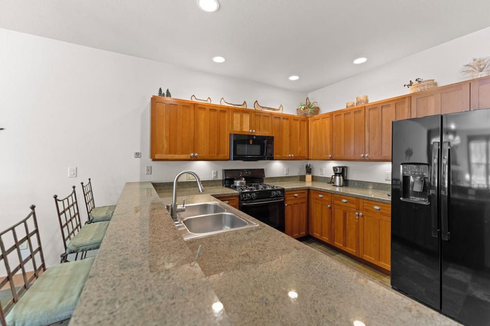 Your fully equipped kitchen features granite counters, modern appliances, and warm wood cabinets—perfect for preparing meals together.