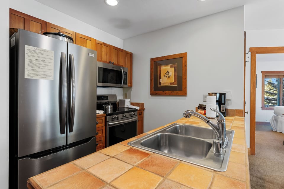 Your fully equipped kitchen features modern stainless steel appliances and warm tile countertops, perfect for preparing meals during your mountain getaway.