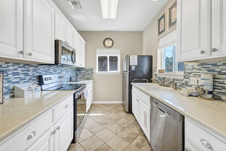 Your fully equipped kitchen awaits with modern appliances and stunning blue glass tile backsplash, perfect for preparing vacation meals together.