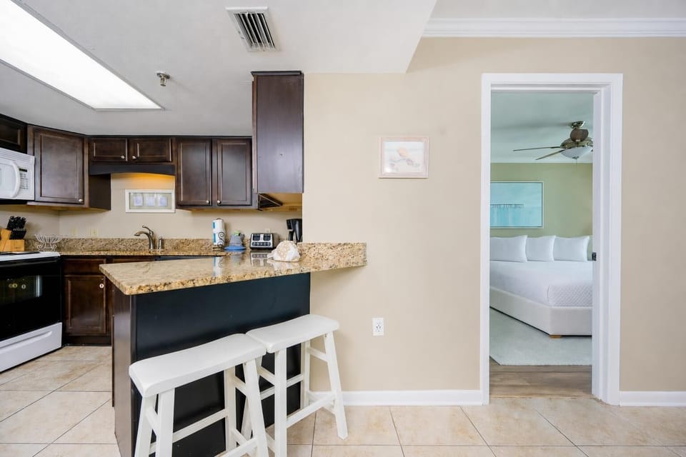 Bright kitchen with granite breakfast bar invites you to sip morning coffee before the day at the coast