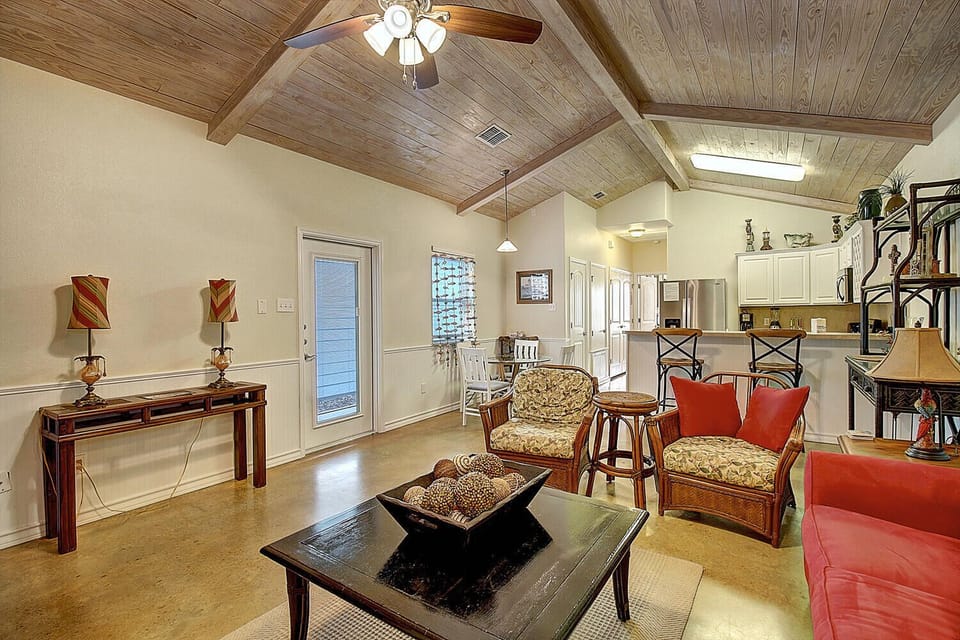 Unwind in this spacious open-concept living area with soaring wood-beam ceilings, comfortable seating, and natural light streaming through skylights.