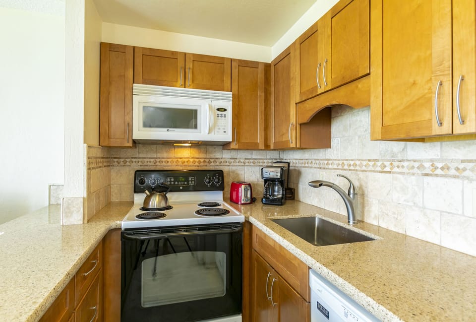 Your fully equipped kitchen awaits with warm wood cabinetry, granite counters, and everything needed to prepare meals during your stay—including a coffee maker to start your mornings right.