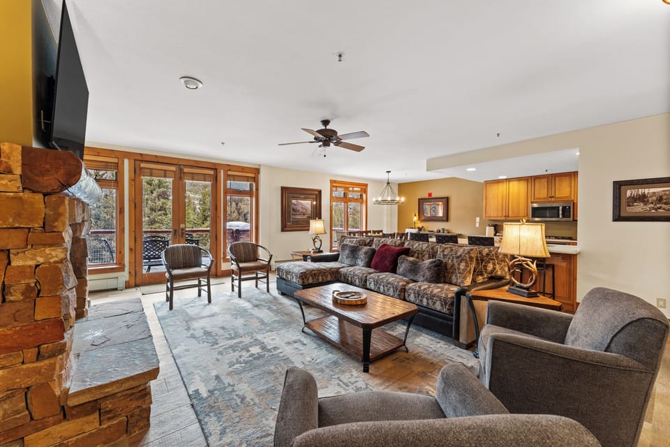 Unwind in your spacious living room with stone fireplace, plush seating, and mountain views through floor-to-ceiling windows.