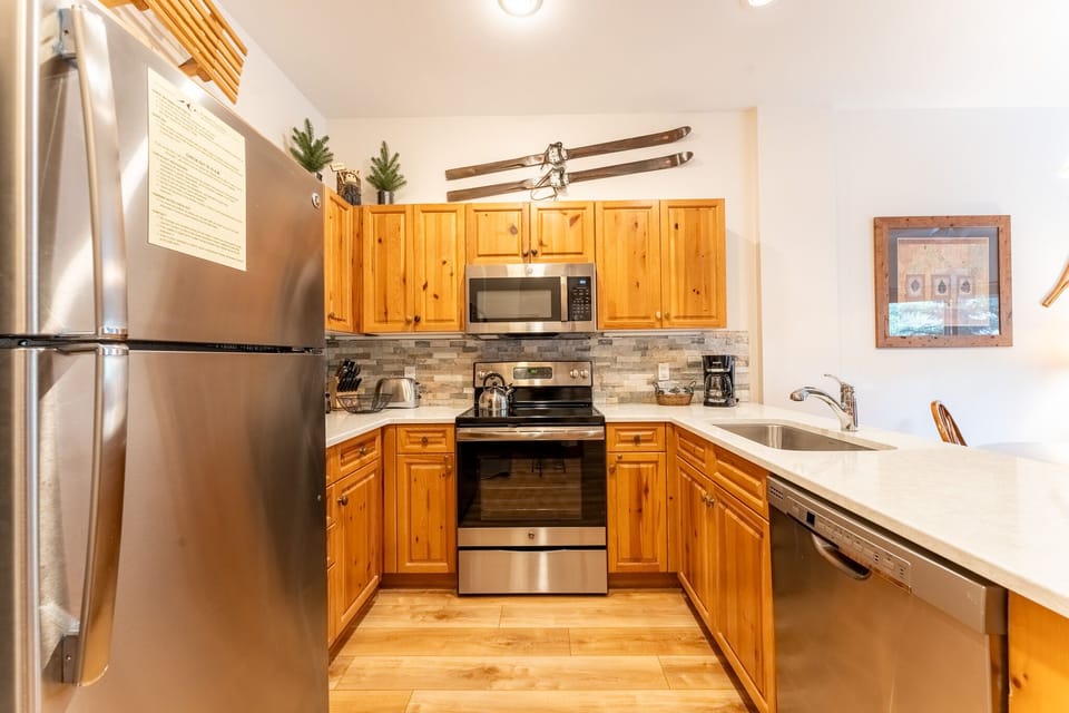 Your fully equipped kitchen awaits with warm wood cabinets, stainless steel appliances, and charming mountain decor for memorable meal preparation.