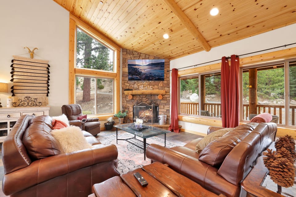 Cozy mountain living room with a stone fireplace, comfy seating, and smart TV—perfect for relaxing evenings, movie nights, and warm cabin vibes after outdoor adventures.