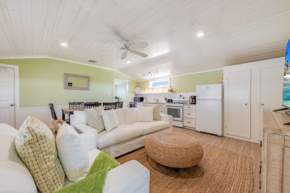 Relax in this bright open-concept living space where coastal charm meets comfort, featuring a fully equipped kitchen and cozy seating area.
