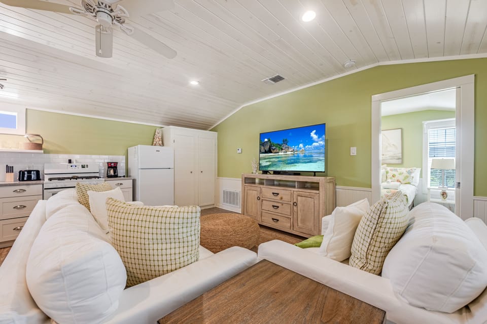 Relax in your coastal-themed living space with plush seating, tropical beach TV, and convenient kitchenette for your perfect getaway.
