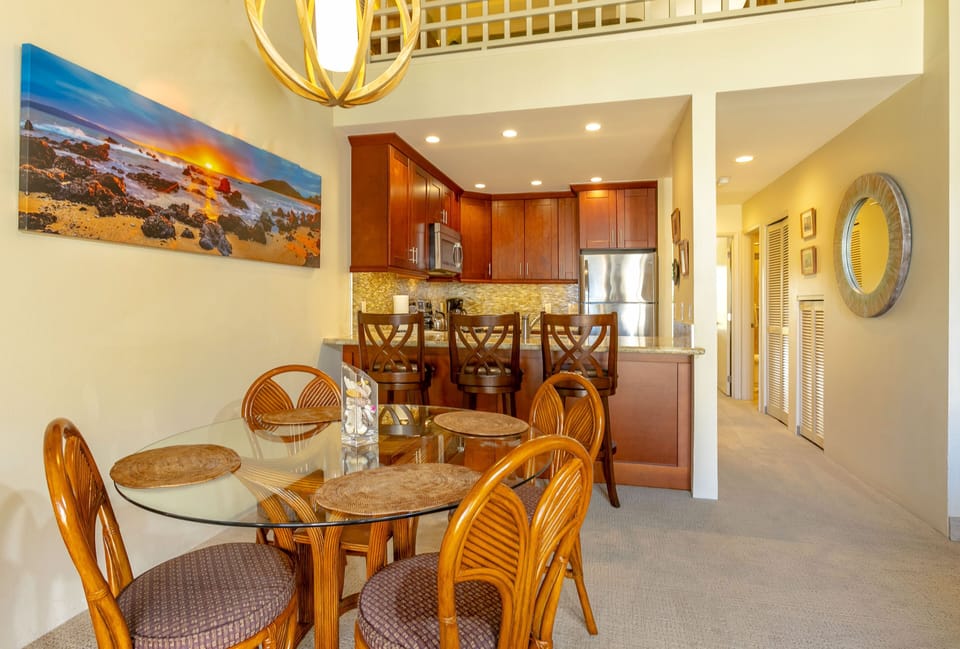 Your open-concept dining and kitchen area features warm wood cabinetry, modern appliances, and a breakfast bar—perfect for enjoying meals together after exploring the coast.