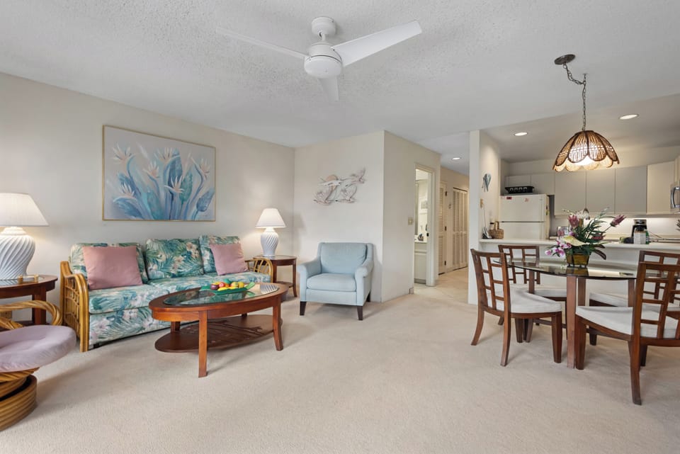 Relax in your spacious living area featuring coastal decor, comfortable seating, and a fully equipped kitchen perfect for preparing meals together during your tropical getaway.