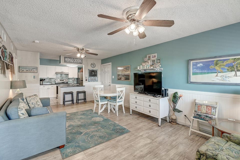 Relax in this bright, coastal-themed space where turquoise walls and beach artwork create your perfect seaside retreat.