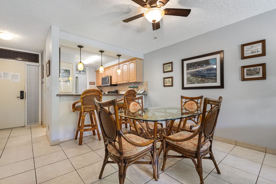 Gather around this charming dining table with comfortable woven chairs, perfect for enjoying meals together. The open layout flows into your fully-equipped kitchen, creating a welcoming space for your stay.