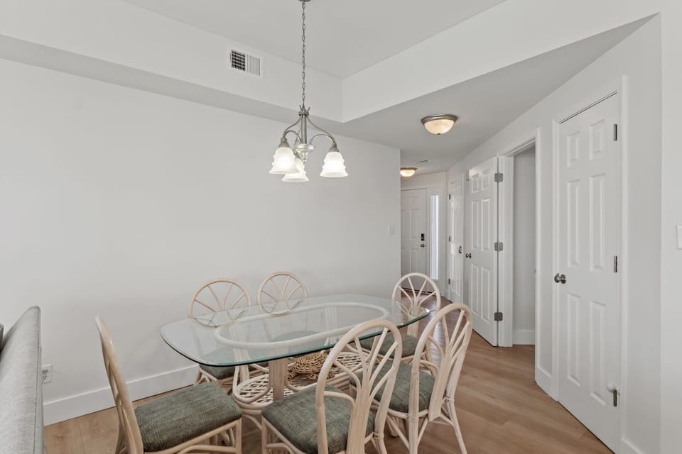 Gather around your elegant glass dining table for memorable meals together in this beautifully lit coastal-inspired space.