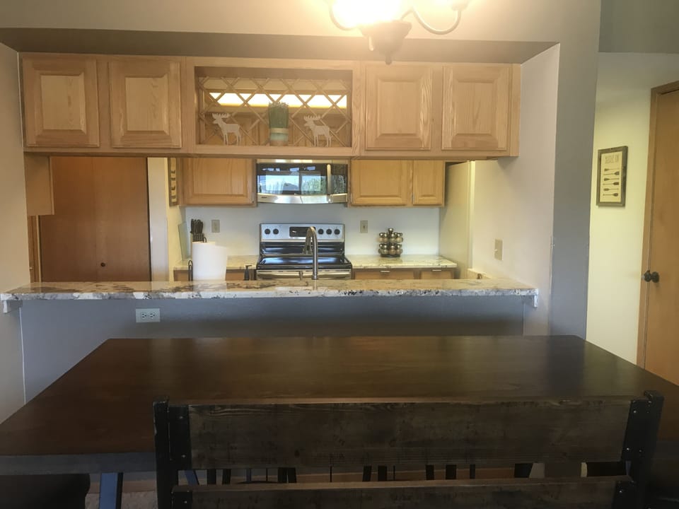 Dining room table, seating for 6, looking into kitchen with granite countertops.