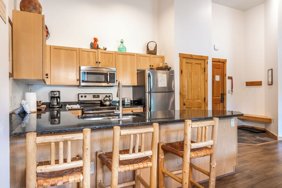Your fully equipped kitchen features granite counters and stainless appliances, perfect for preparing mountain meals with friends gathered around the breakfast bar.