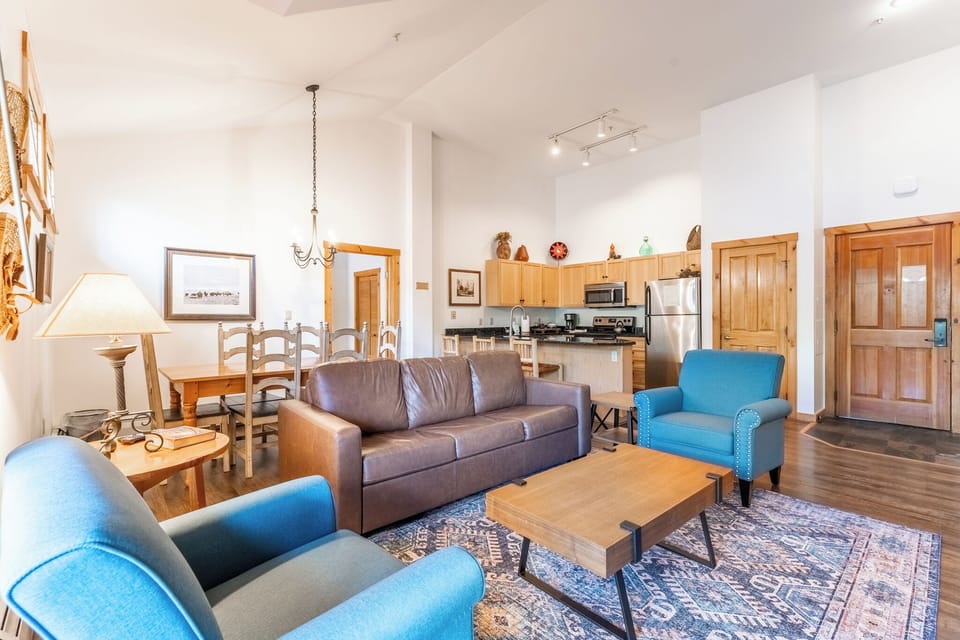 Relax in your spacious open-concept living area with comfortable seating, fully equipped kitchen, and warm mountain lodge finishes.