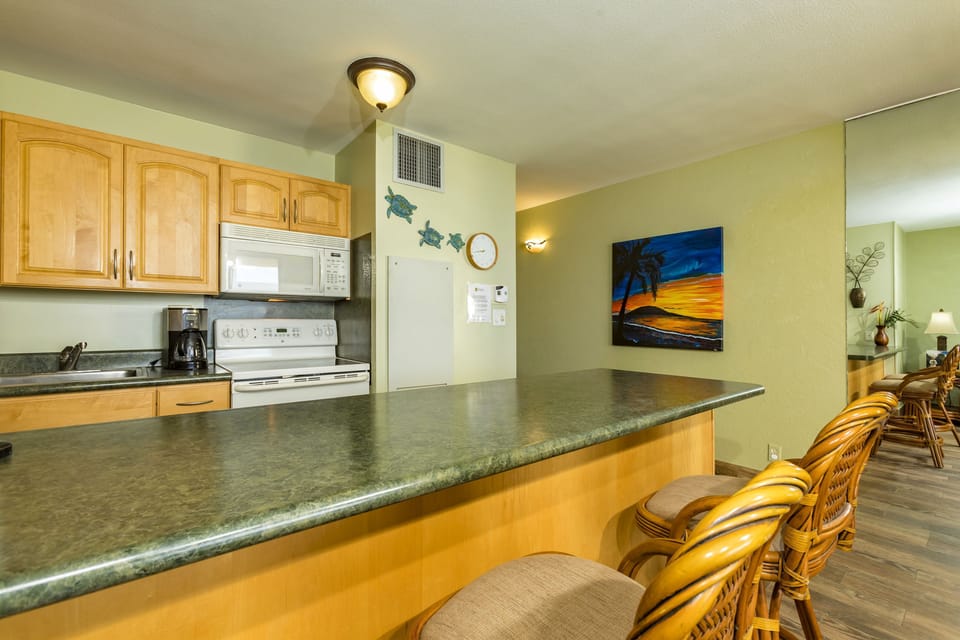 Spacious kitchen with natural wood cabinets, granite countertops, and a welcoming breakfast bar where you can enjoy morning coffee while planning your island adventures.