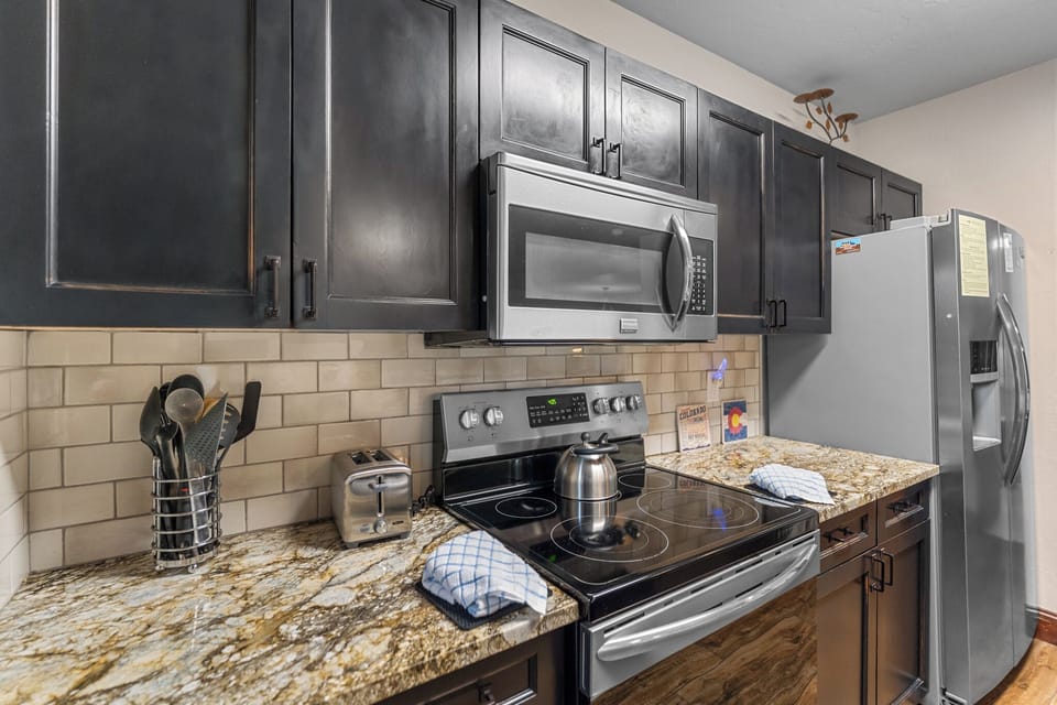 Full kitchen with granite countertops, stainless steel appliances, and breakfast bar seating.