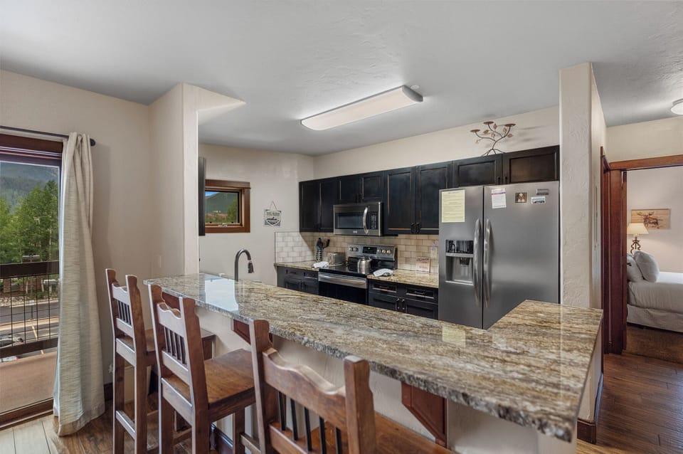 Full kitchen with granite countertops, stainless steel appliances, and breakfast bar seating.