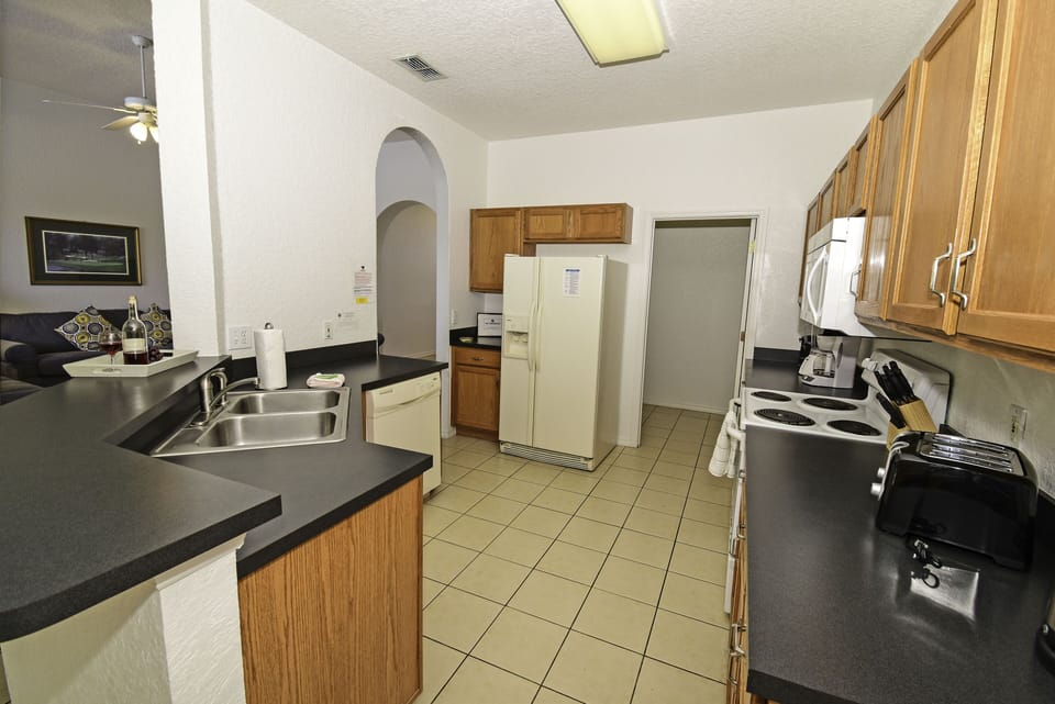 Fully equipped kitchen with tiled flooring and breakfast bar.
