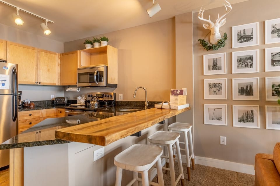 Your gourmet kitchen features warm wood cabinetry, granite countertops, and a stunning live-edge breakfast bar perfect for morning coffee.