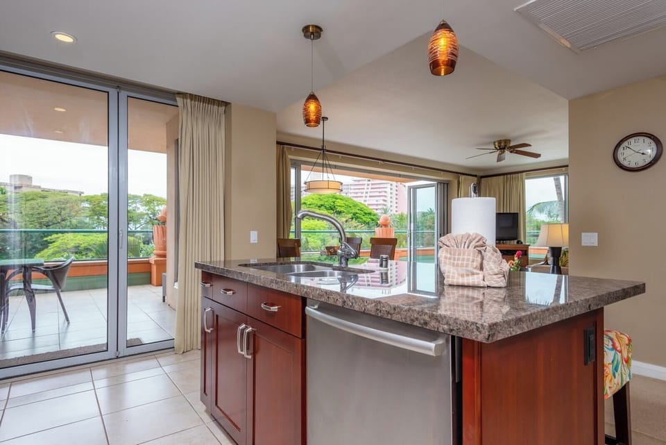 Granite kitchen island with pendant lighting and scenic lanai access