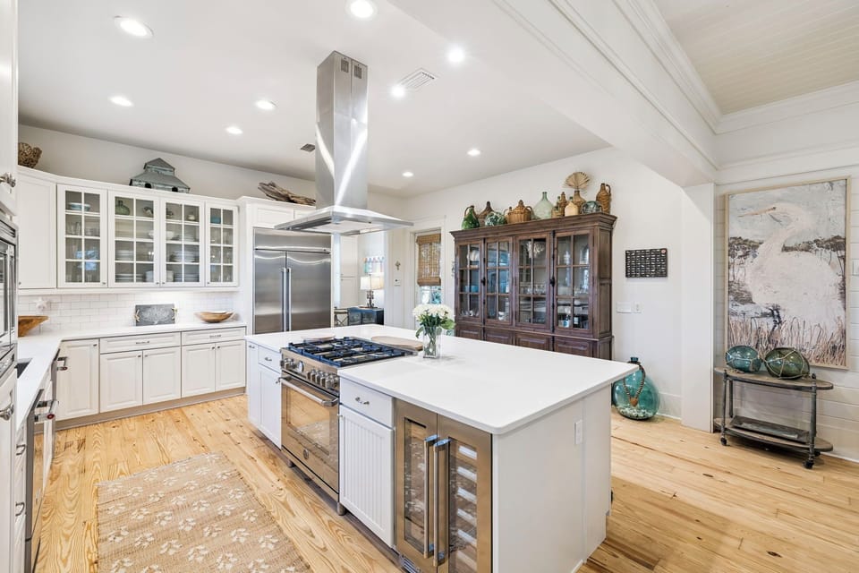 Your gourmet kitchen awaits with professional appliances, spacious marble island, and charming coastal touches throughout this bright, airy space.